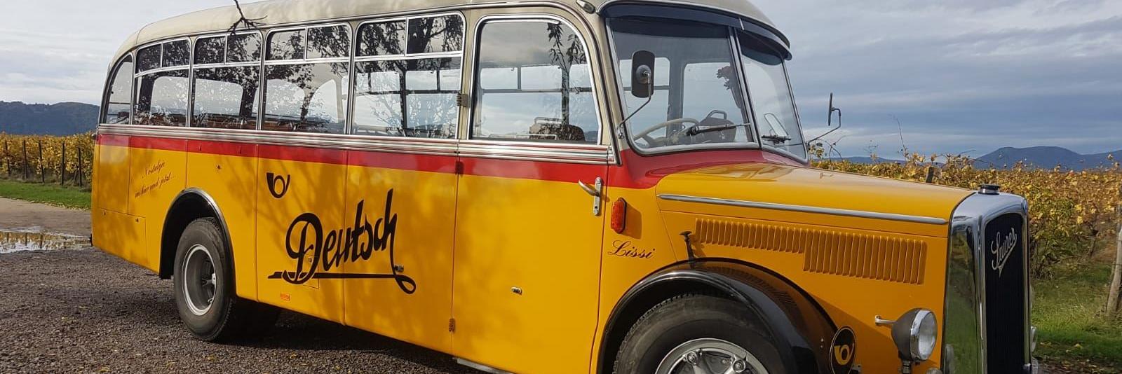 gelber Oldtimer Postbus vor blauem Himmel