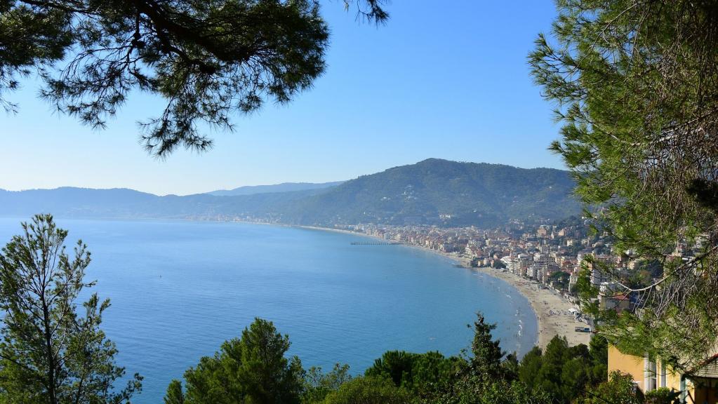 Allasio an der Blumenriviera mit Blick durch Bäume auf das Wasser