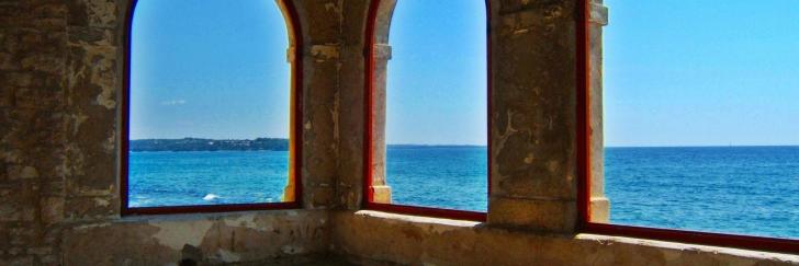 Blick durch Fenster aus Stein auf das Meer und den Himmel