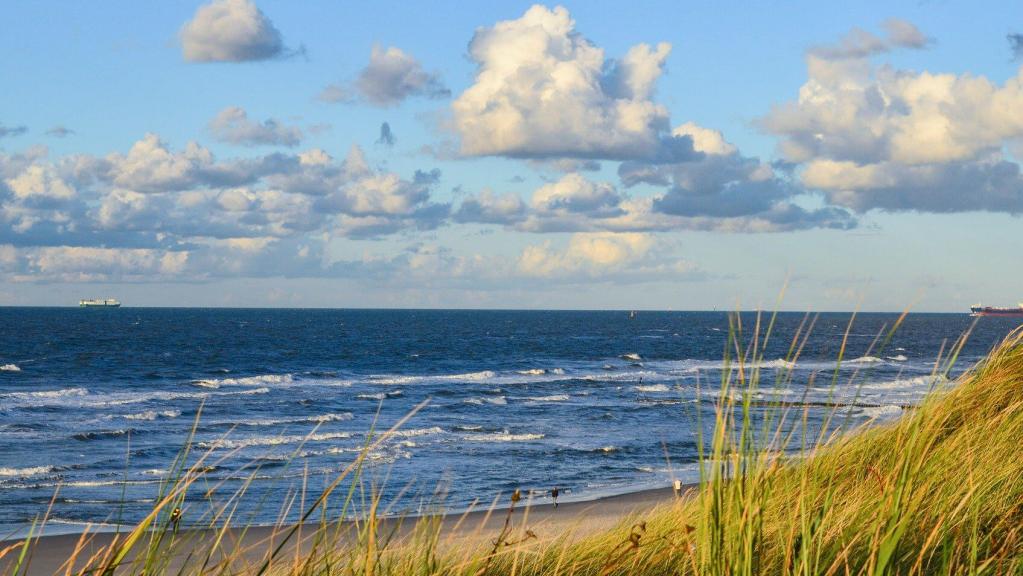 Nordseestrand mit Dünen, blaues Wasser und Wolken am Himmel